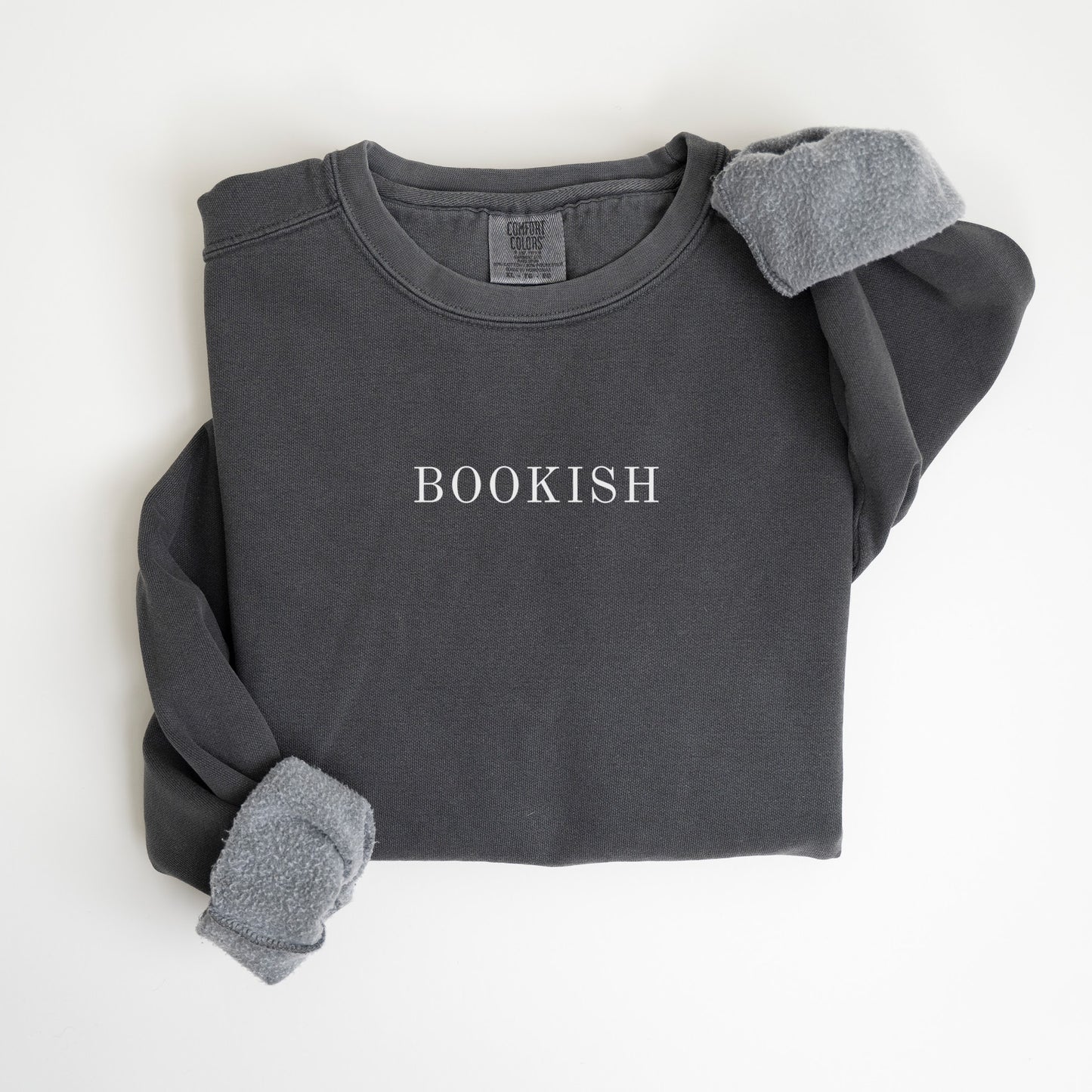 A folded unisex Comfort Colors sweatshirt in pepper color with the word 'BOOKISH' printed in a simple, classic font on the front.