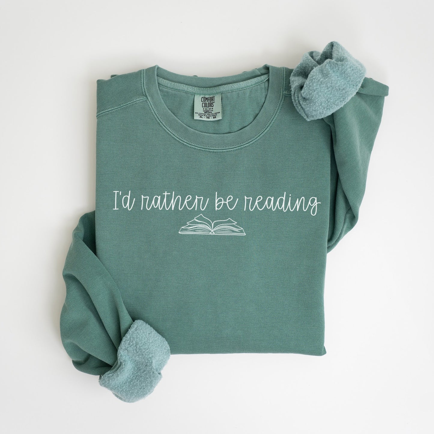 A folded unisex Comfort Colors sweatshirt in light green with the phrase 'I'd rather be reading' printed above a simple line drawing of an open book.