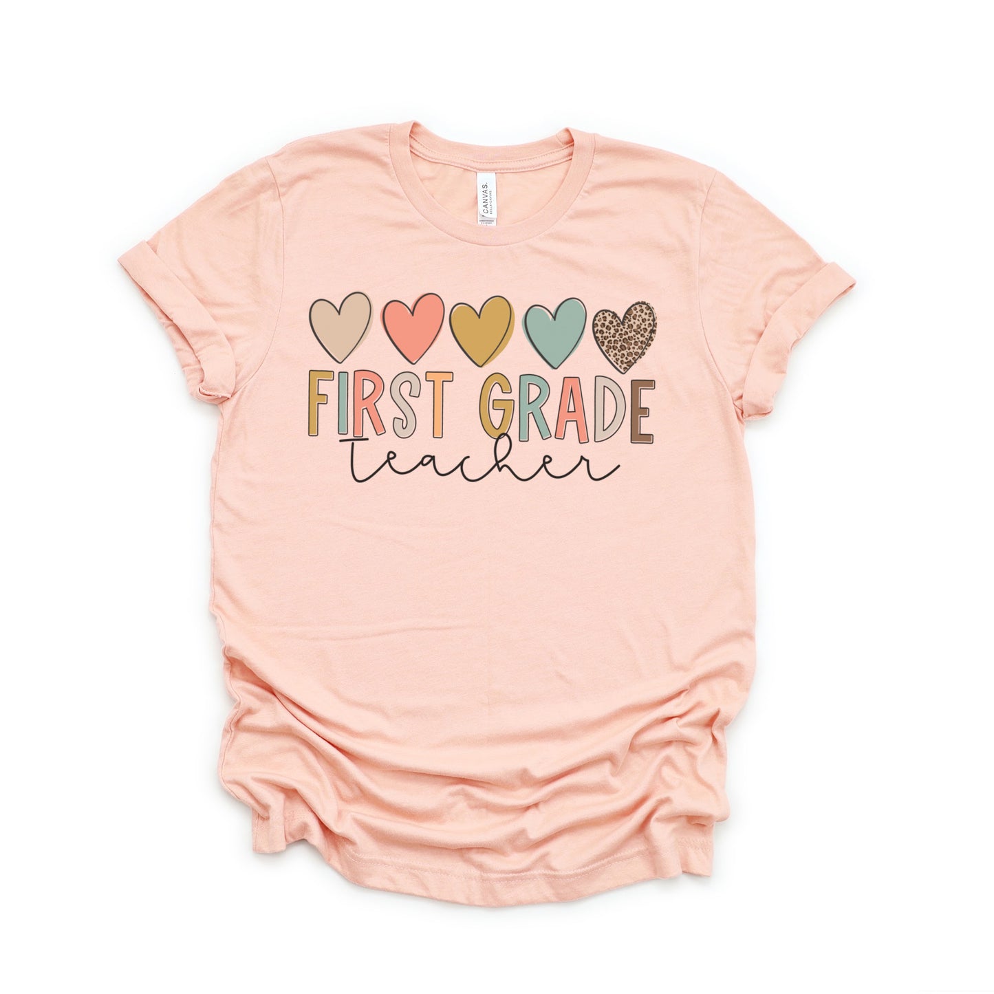 5 hearts in a row, all different colors and one cheetah print. "first grade teacher" underneath the hearts, "ifrst grade" text is each different colors. "teacher" in cursive underneath. Women Unisex Tshirt Color: Heather Peach