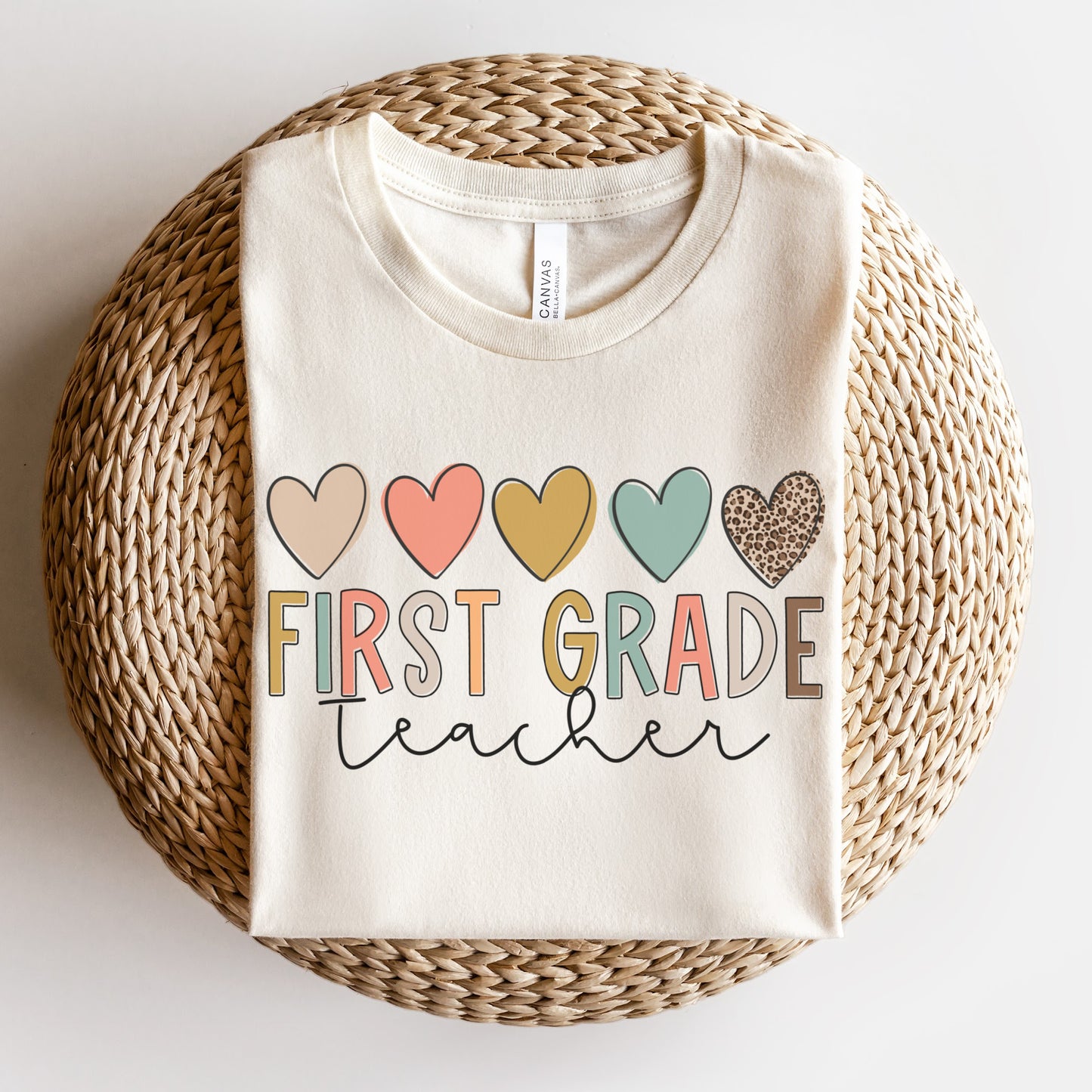 5 hearts in a row, all different colors and one cheetah print. "first grade teacher" underneath the hearts, "ifrst grade" text is each different colors. "teacher" in cursive underneath. Women Unisex Tshirt Color: Natural