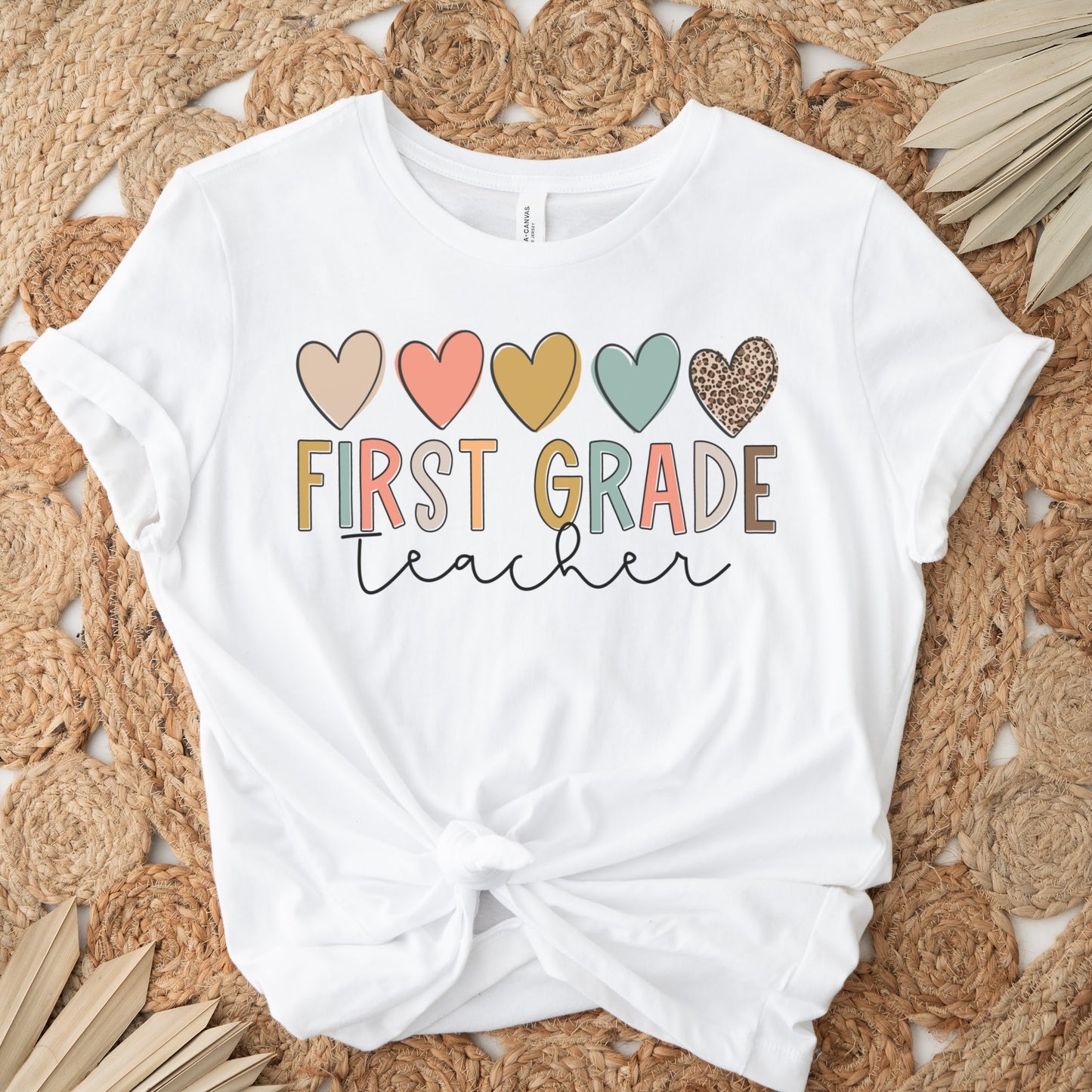 5 hearts in a row, all different colors and one cheetah print. "first grade teacher" underneath the hearts, "ifrst grade" text is each different colors. "teacher" in cursive underneath. Women Unisex Tshirt Color: White