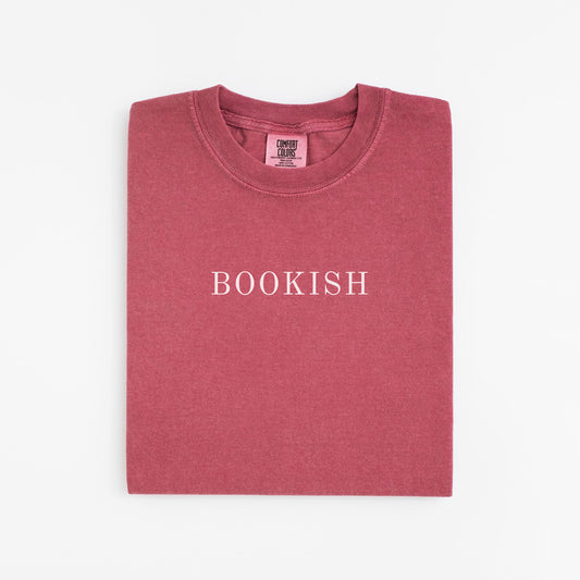 A folded unisex Comfort Colors t-shirt in crimson color with the word 'BOOKISH' printed in a simple, classic font on the front.