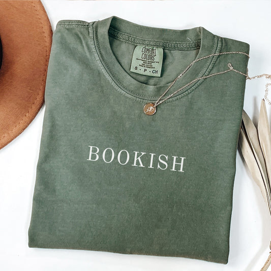 A folded unisex Comfort Colors t-shirt in moss color with the word 'BOOKISH' printed in a simple, classic font on the front.