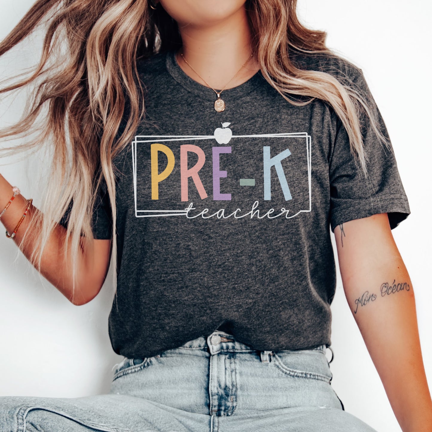 Pre-K teacher tshirt with multicolor font. White rectangle border and apple. Dark Grey Heather color