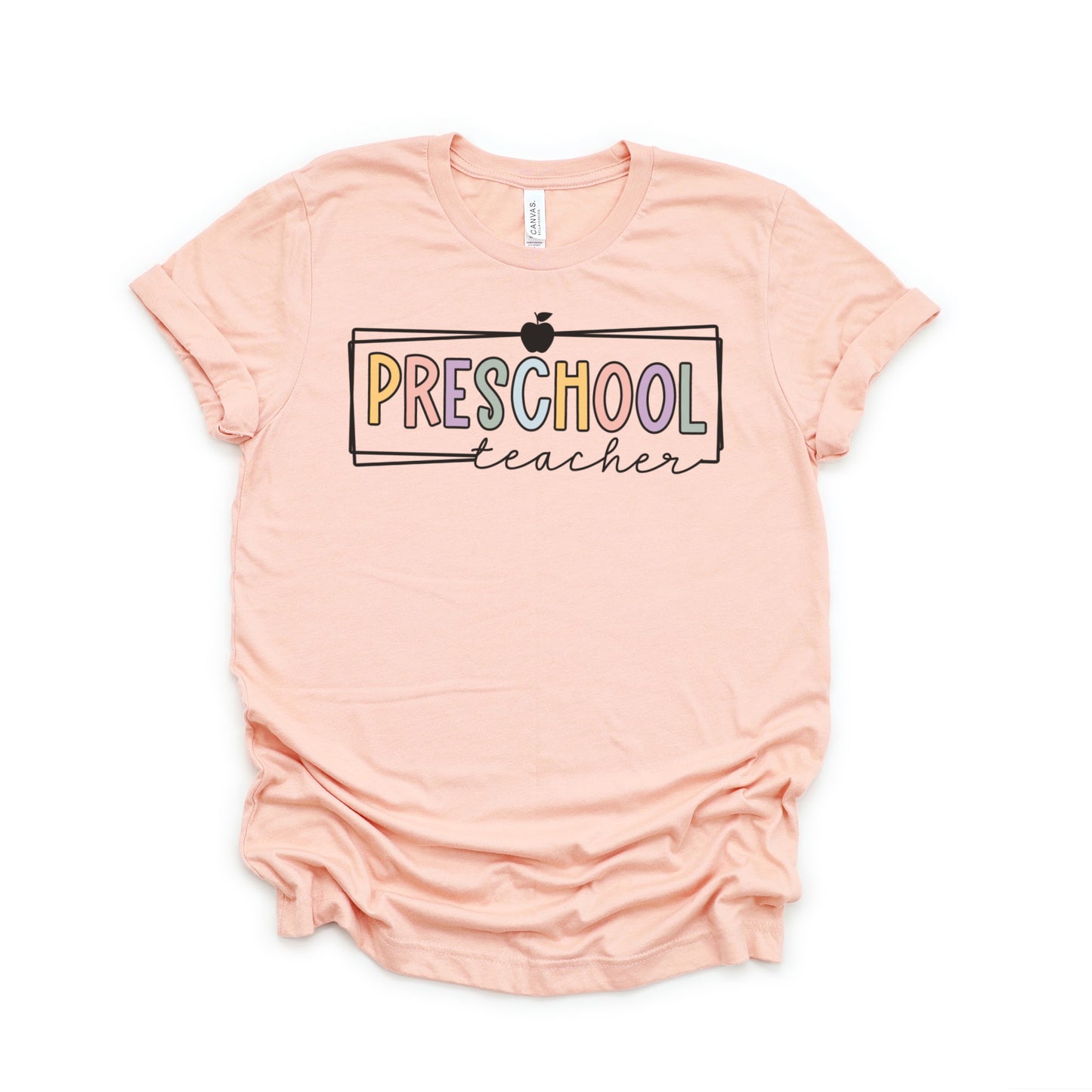 Preschool Teacher Tshirt Multicolor font with white rectangle borders and an apple on the top. Heather Peach Color